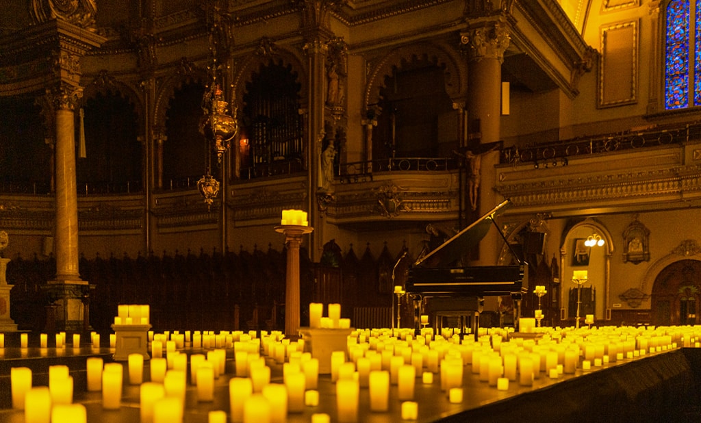 Concert Candlelight dans l'Église St-Jean-Baptiste à Montréal, un piano est au centre de la scène entouré de bougies 